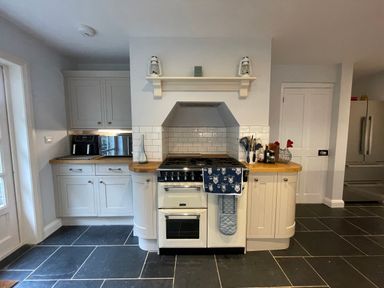 A kitchen with a stove oven and utensils on wooden countertops at Bryn Awelon in Harlech