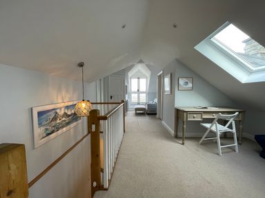 A hallway with a desk and chair under a skylight a hanging light and a seating area at Bryn Awelon in Harlech