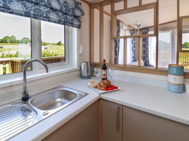 A kitchen countertop with a sink kettle wine bottle bread and tomatoes at Maple Lodge in Whitby