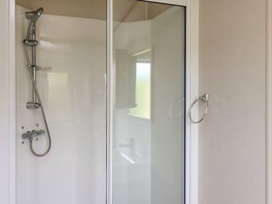 A shower area with a sliding glass door a handheld showerhead and a towel ring on the wall at Maple Lodge in Whitby