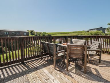 A deck area with wooden furniture at Maple Lodge in Whitby