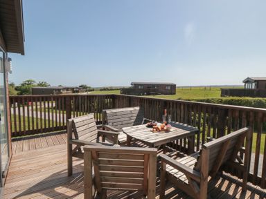 An outdoor area with a wooden table and chairs at Maple Lodge in Whitby