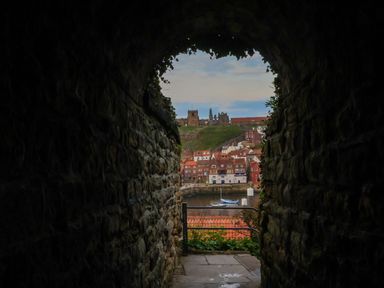 A view of buildings and a boat through an archway at Fir Lodge in Whitby