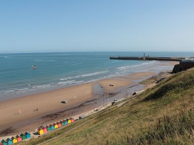 A beach with huts and a pier at Fir Lodge in Whitby