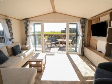 A living room with a sliding door leading to the deck at Fir Lodge in Whitby