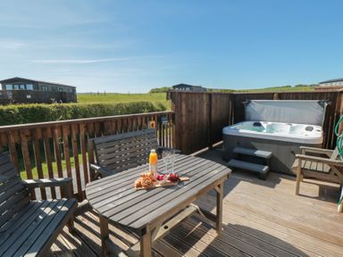A deck with a hot tub and table setting at Fir Lodge in Whitby
