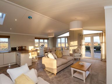 A living room with sofas a coffee table dining area and kitchen at Cherry Blossom Lodge in Whitby