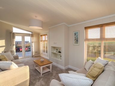 A living room with sofas a coffee table and windows with blinds at Cherry Blossom Lodge in Whitby