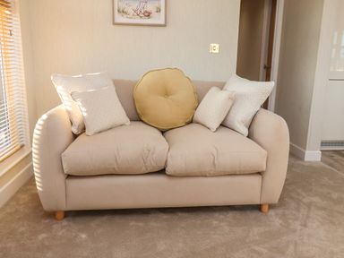 A beige sofa with five cushions in a room with beige carpet at Cherry Blossom Lodge in Whitby