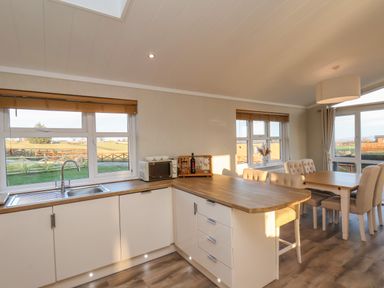 A kitchen area with a wooden countertop next to a dining table with chairs in a room at Cherry Blossom Lodge in Whitby