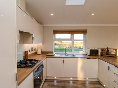 A kitchen with a stove oven microwave sink and window with a view at Cherry Blossom Lodge in Whitby