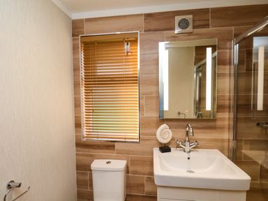 A bathroom with a toilet sink mirror and window blinds at Cherry Blossom Lodge in Whitby