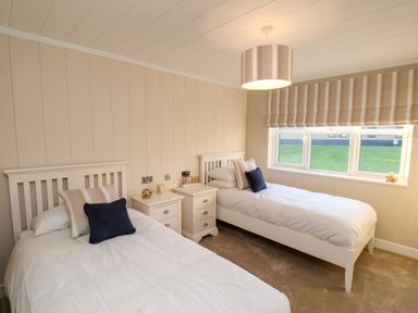A bedroom with two single beds and a window with striped blinds at Cherry Blossom Lodge in Whitby