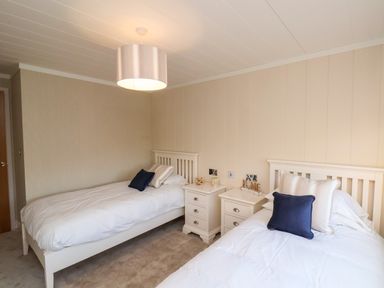 A bedroom with two single beds side by side and two bedside tables in between at Cherry Blossom Lodge in Whitby