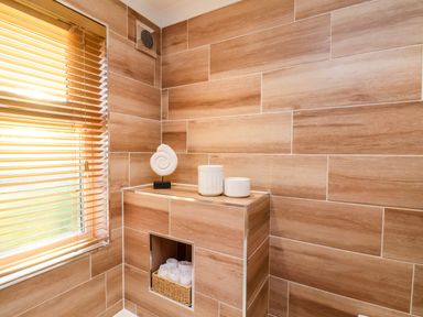 A bathroom corner with wooden tile walls a window with blinds decorative jars and a shell sculpture at Cherry Blossom Lodge Whitby