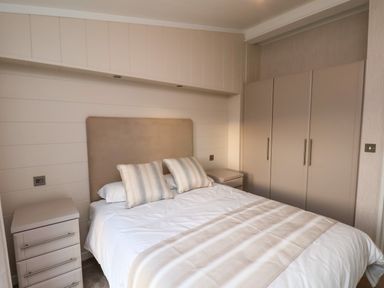 A bedroom with a double bed two bedside tables and a wardrobe at Holly Lodge Whitby