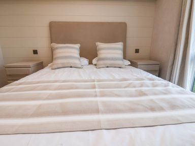 A bed with two striped pillows and a striped blanket between two bedside tables at Holly Lodge in Whitby