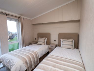 A bedroom with two single beds and a window at Holly Lodge in Whitby