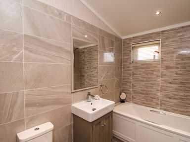 A bathroom with a bathtub sink mirror and toilet at Holly Lodge in Whitby