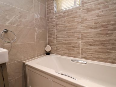A bathroom with a bathtub a towel ring and tiled walls at Holly Lodge in Whitby