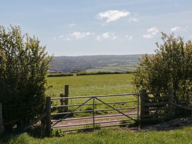 A gate leading to a field with hills in the background at Holly Lodge, Whitby