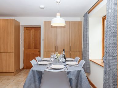 A dining room with a table set for six with plates glasses and cutlery at The Old Coach House in Little Dunley Cottages near Bovey Tracey