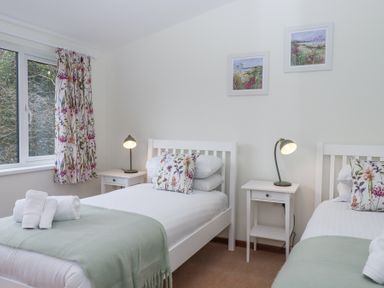 A bedroom with two single beds floral curtains and bedside tables with lamps at The Old Coach House Little Dunley Cottages near Bovey Tracey