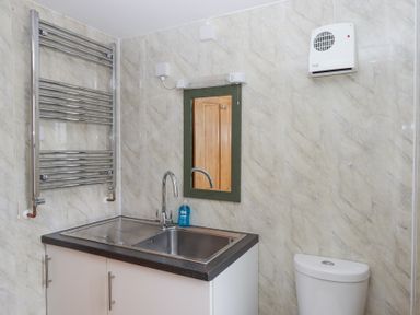 A bathroom with a sink, mirror, towel radiator, and toilet at The Old Coach House in Little Dunley Cottages near Bovey Tracey