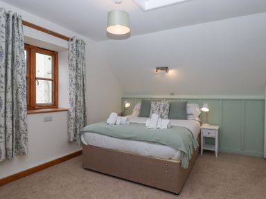 A bedroom with a double bed pillows bedside table and lamps at The Old Coach House Little Dunley Cottages near Bovey Tracey