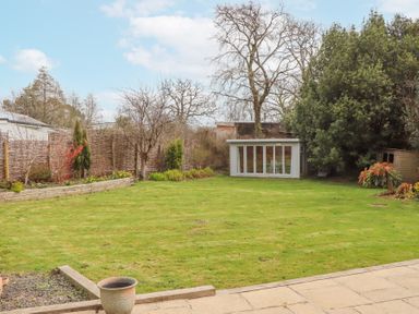 A garden with a lawn wooden fence trees and a shed at The Old Coach House Little Dunley Cottages near Bovey Tracey