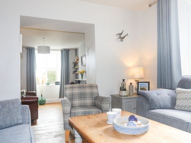 A living room with two blue sofas grey armchair wooden coffee table and a lamp at School House in Aberffraw