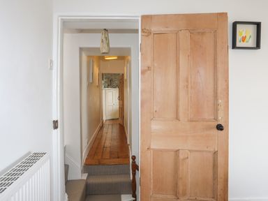 A hallway with wooden floor and a partly open wooden door at School House in Aberffraw