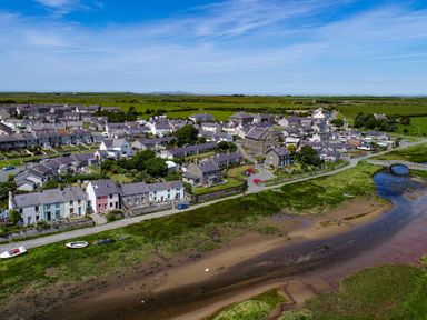 A small town with houses near a river and green fields at School House in Aberffraw