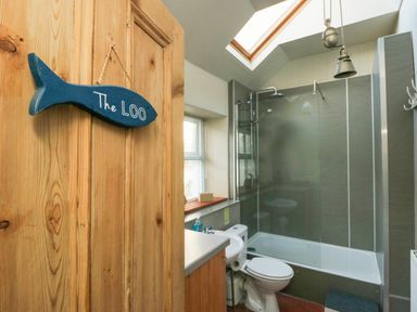 A bathroom with a toilet sink shower and skylight at School House in Aberffraw