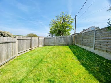 A grassy garden enclosed by wooden fences and a tree near a house at Hawthorn in Crackington near Crackington Haven