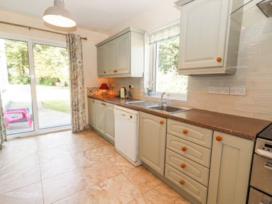 A kitchen with cabinets a dishwasher sink and sliding glass doors leading outside at Dromclough Farmhouse in Dromclough near Listowel County Kerry