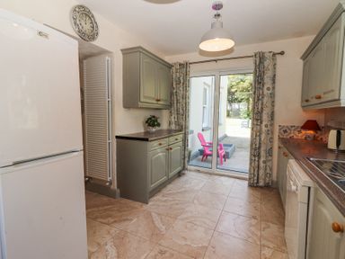 A kitchen with cabinets a refrigerator sliding glass doors showing patio at Dromclough Farmhouse in Dromclough near Listowel County Kerry