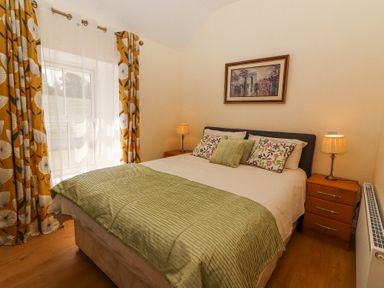 A bedroom with a bed pillows lamps curtains and a framed picture at Dromclough Farmhouse in Dromclough near Listowel County Kerry