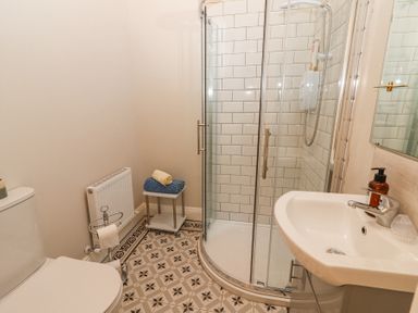 A bathroom with a toilet, a glass shower enclosure, a sink, a radiator, and towels on a small table at Dromclough Farmhouse in Dromclough near Listowel County Kerry