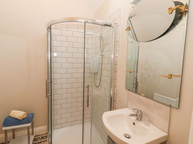 A bathroom with a glass shower enclosure sink with faucet a mirror and towels on a stand at Dromclough Farmhouse in Dromclough near Listowel County Kerry