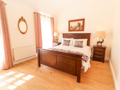 A bedroom with a wooden bed and two bedside tables with lamps at Dromclough Farmhouse in Dromclough near Listowel County Kerry