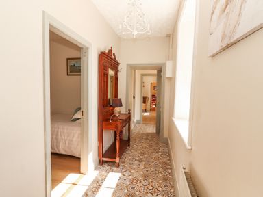 A hallway with patterned floor tiles a wooden table with a mirror and lamp a radiator and doorways at Dromclough Farmhouse in Dromclough near Listowel County Kerry