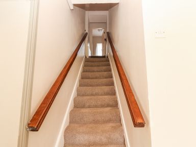 A carpeted staircase with wooden handrails leading to a hallway at Dromclough Farmhouse in Dromclough near Listowel County Kerry