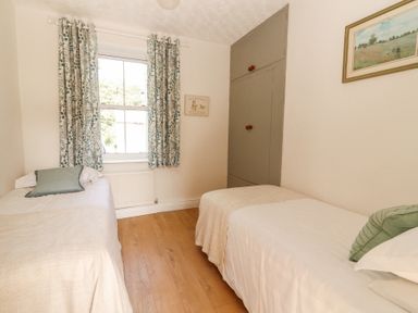 A bedroom with two single beds a window with patterned curtains a built in gray wardrobe and a framed picture on the wall at Dromclough Farmhouse in Dromclough near Listowel County Kerry