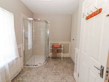 A bathroom with a glass corner shower enclosure a towel rack with towels and a door with hooks at Dromclough Farmhouse in Dromclough near Listowel County Kerry