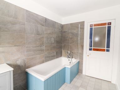 A bathroom with a bathtub and door at Shanti Gher in Bantry