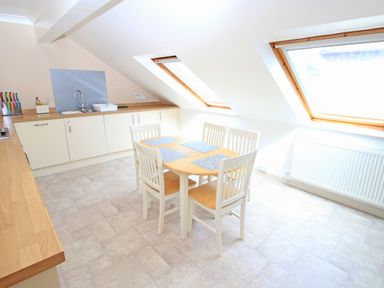 A kitchen with white cabinets wooden countertops a dining table with four chairs and two skylight windows at Fisherman Cove in Porthmadog