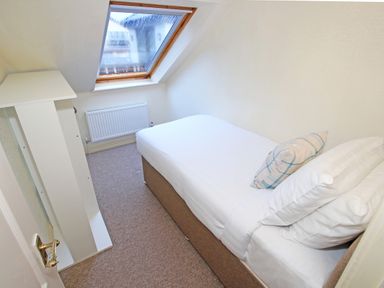 A small bedroom with a single bed and a slanted window at Fisherman Cove in Porthmadog