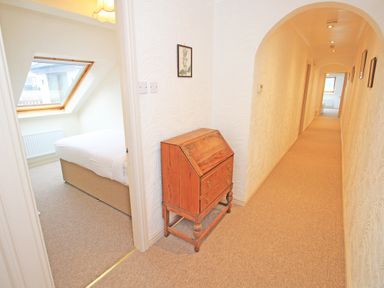 A hallway with an arched ceiling a wooden cabinet and a bedroom with a skylight window at Fisherman Cove in Porthmadog