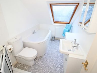 A bathroom with a toilet bathtub sink towels and a window at Fisherman Cove in Porthmadog